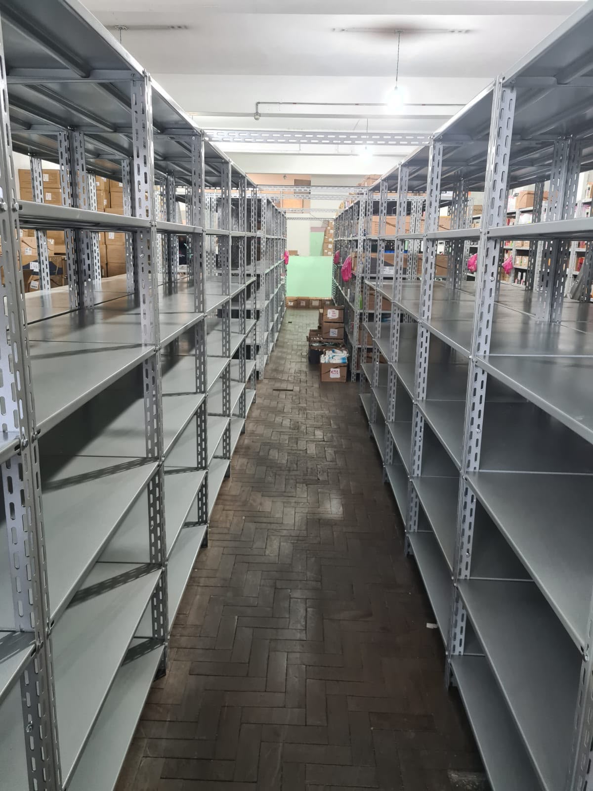 Corredor de estoque com estantes de aço montadas pela AJ Móveis